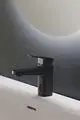 Schwarze Armatur vor einem grau strukturierten Hintergrund. Die Armatur hat einen kräftigen Wasserhahn und eine moderne Steuerung. Ideal Standard macht dieses Produkt für zeitgemäße Badezimmer.